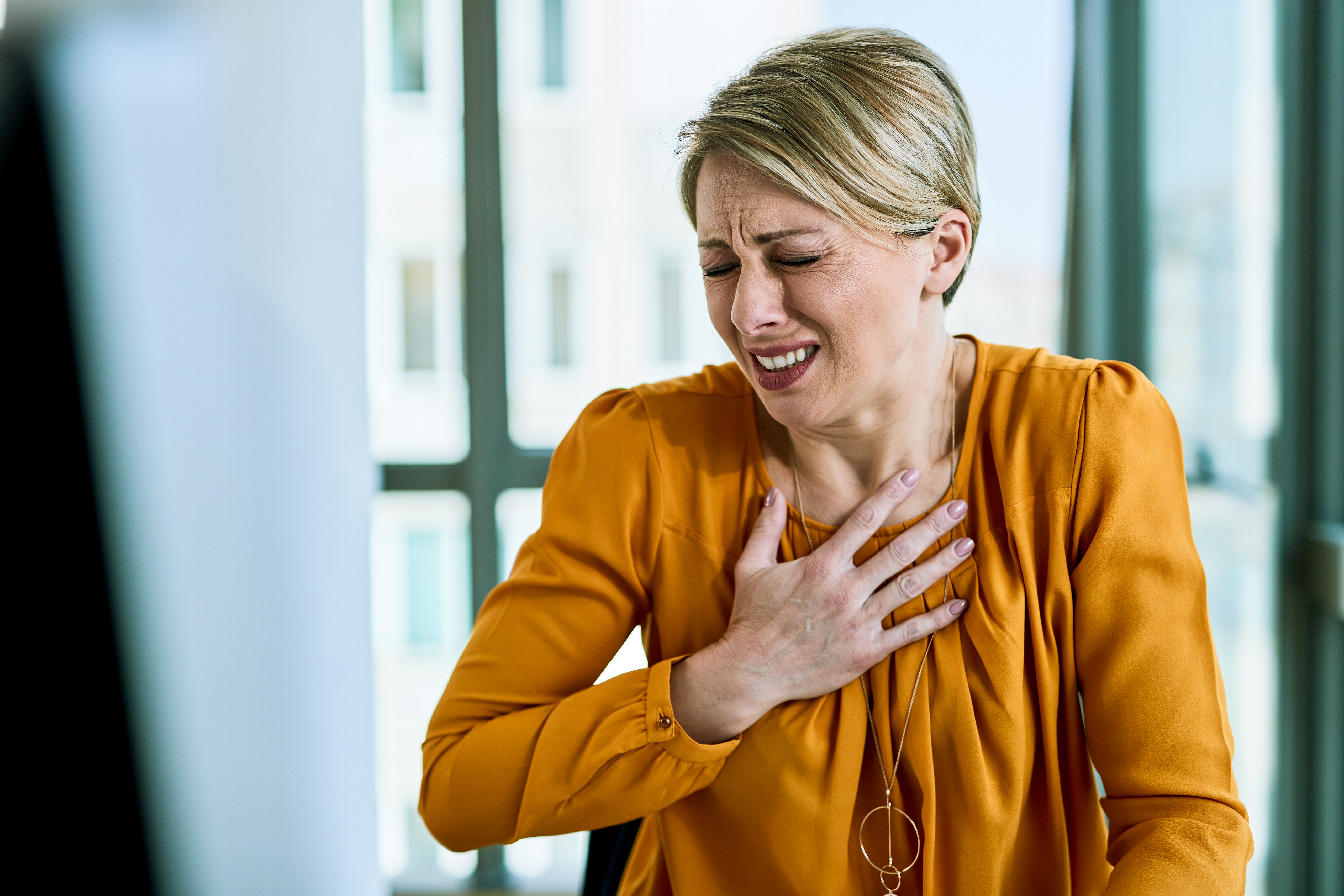 Woman experiencing chest discomfort linked to iron deficiency symptoms.